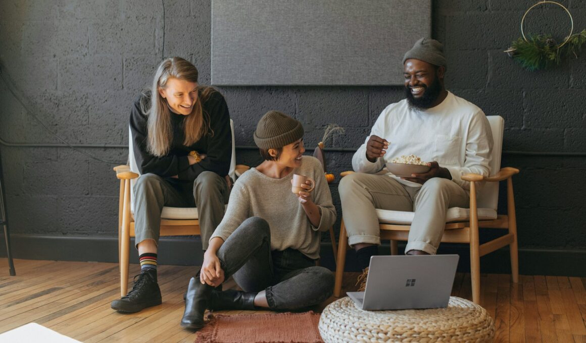 Three coworkers sitting together laughing Surface laptop on furniture